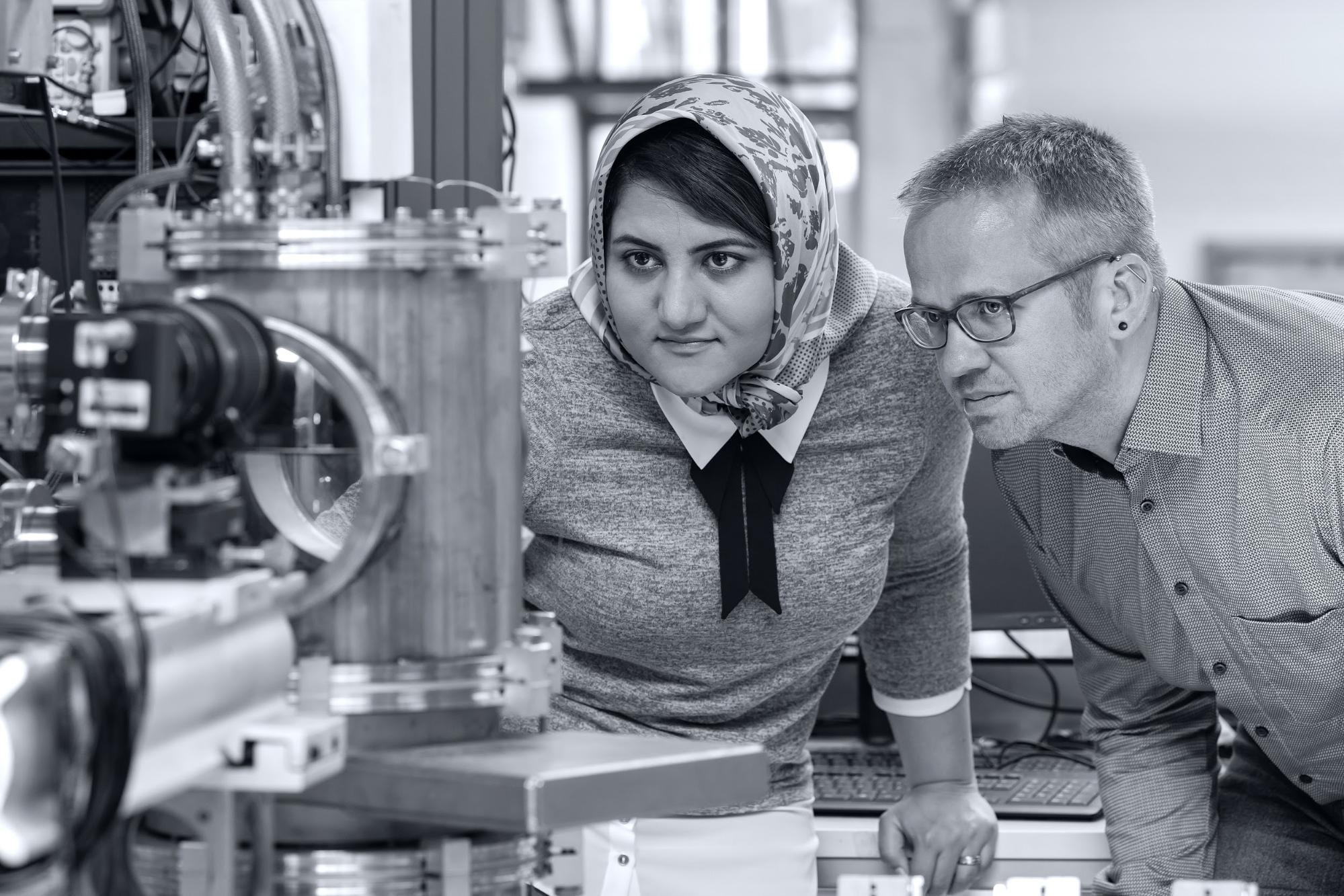 Two people watching molten metal droplets